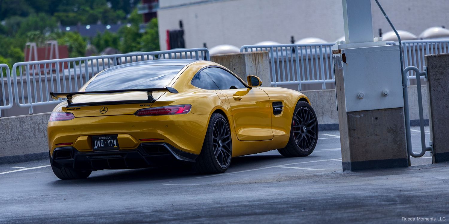 Yellow Mercedes-AMG GT coupe on wet pavement at a car meet.