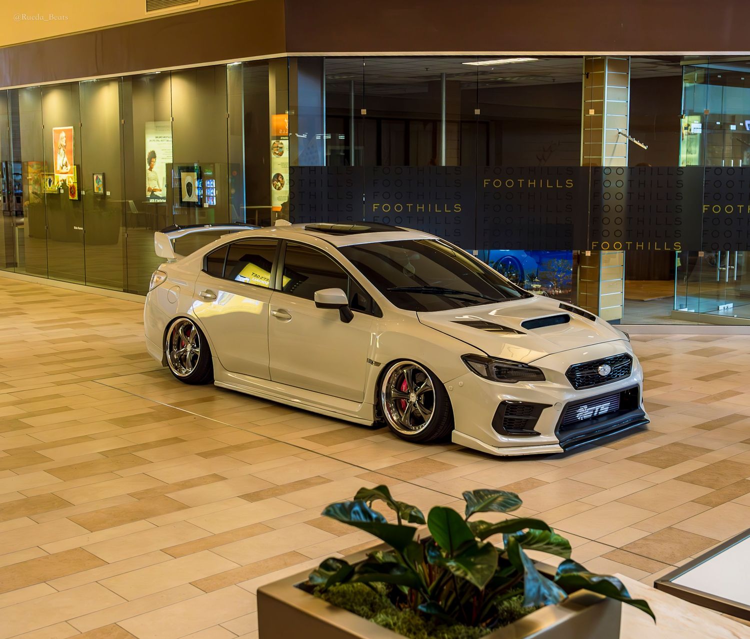 White Subaru WRX STI bagged on custom wheels displayed at Foothills mall show.