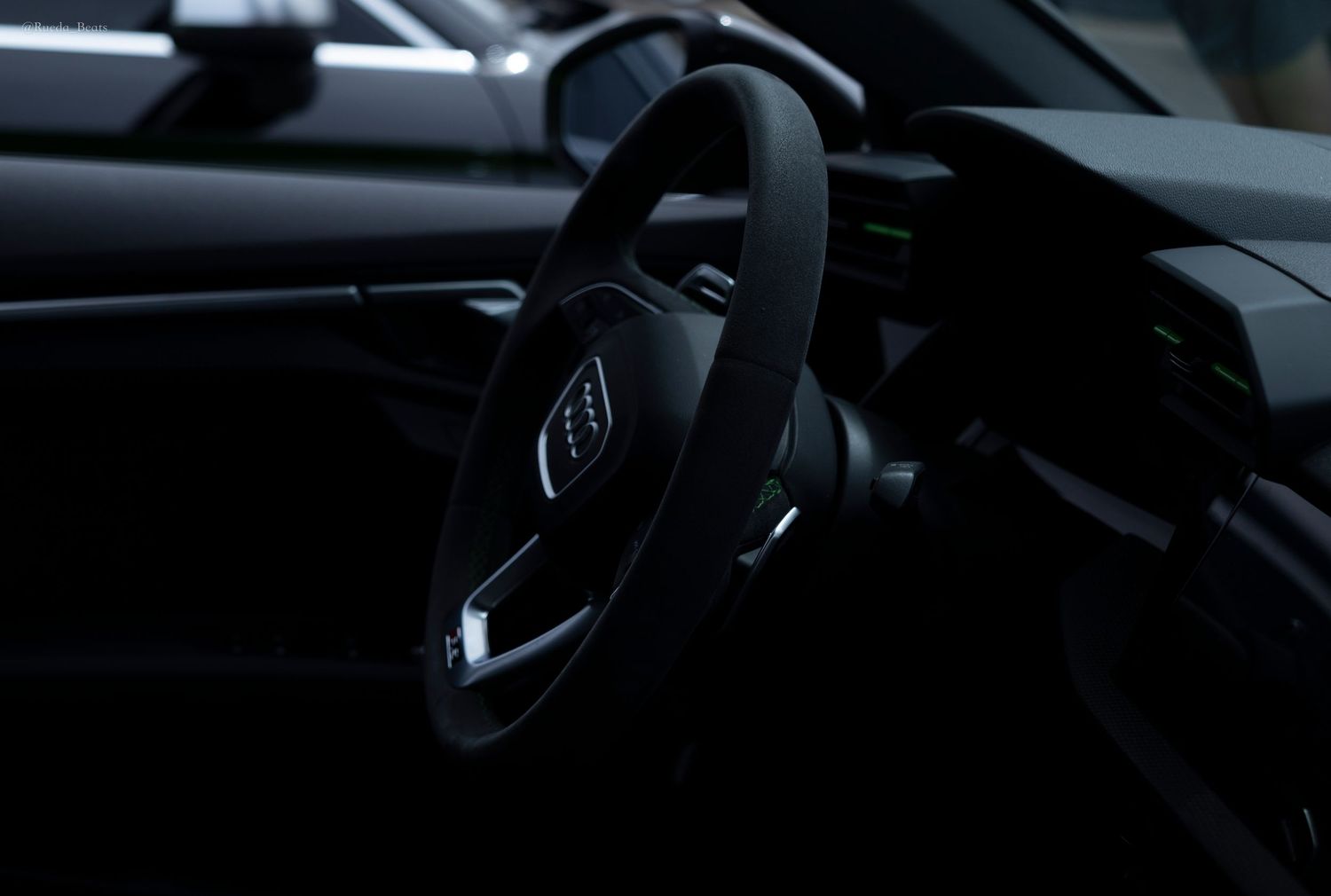 Dark Audi interior featuring a flat-bottom steering wheel.