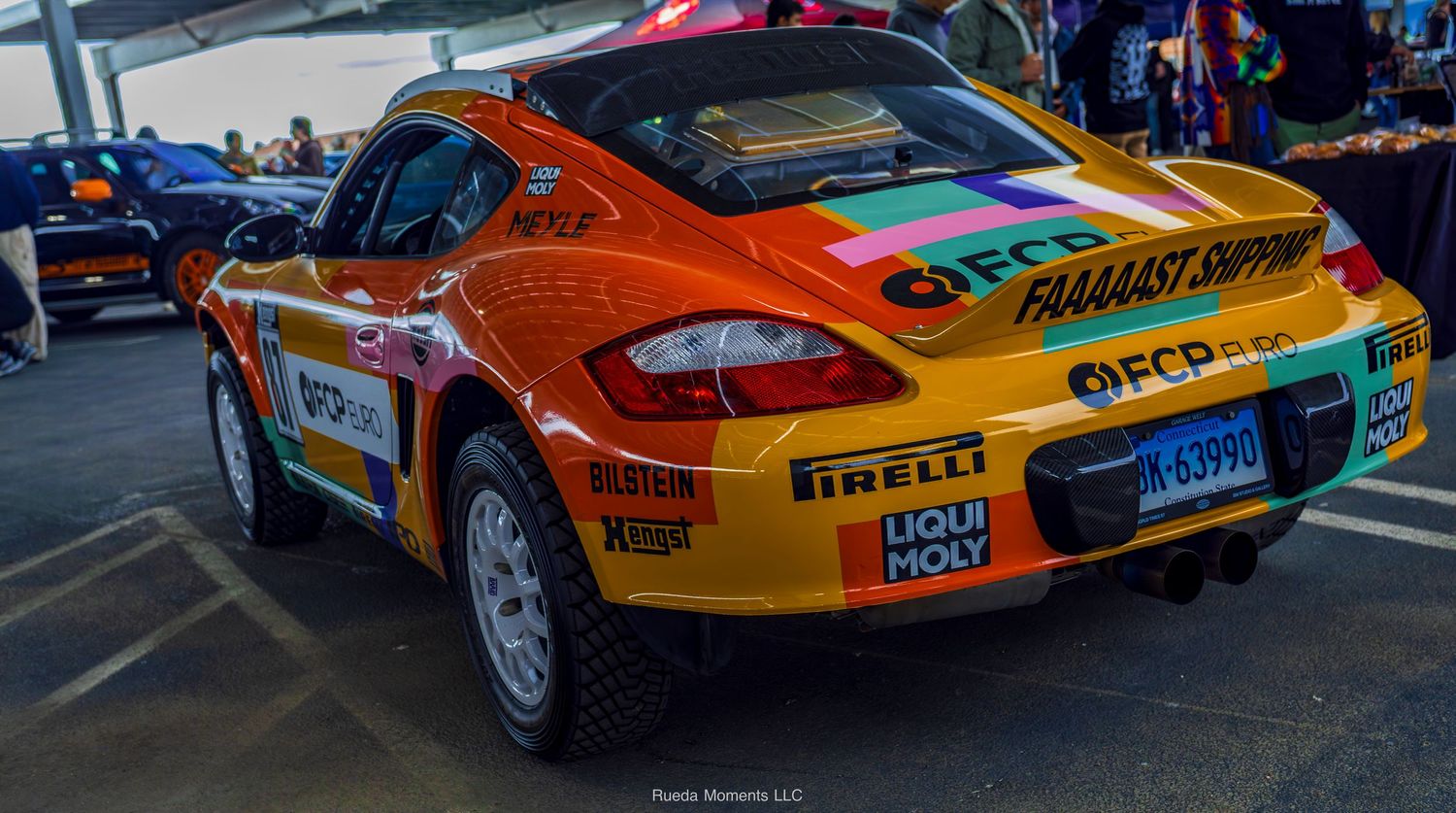 Orange Porsche Cayman rally car with Pirelli and Liqui Moly livery.