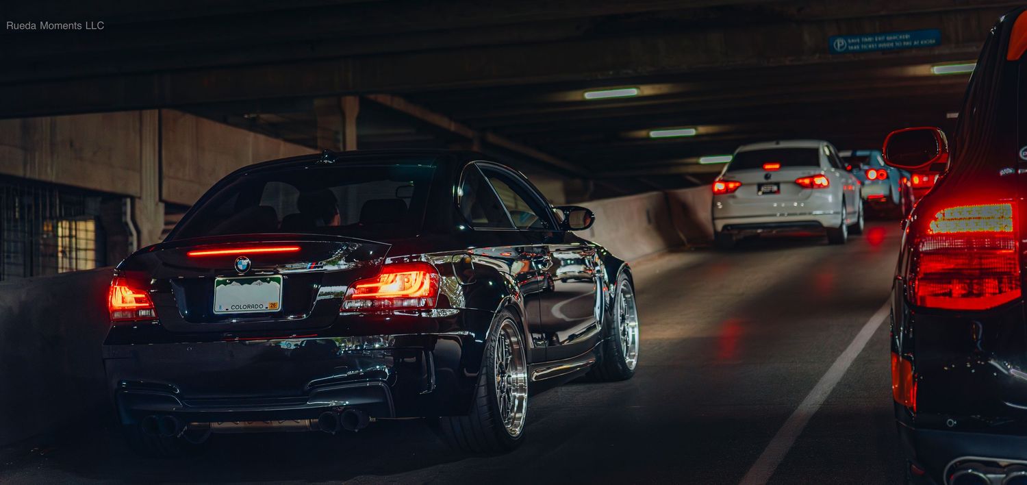 Three modified cars driving through a dark tunnel with red brake lights illuminating the scene.