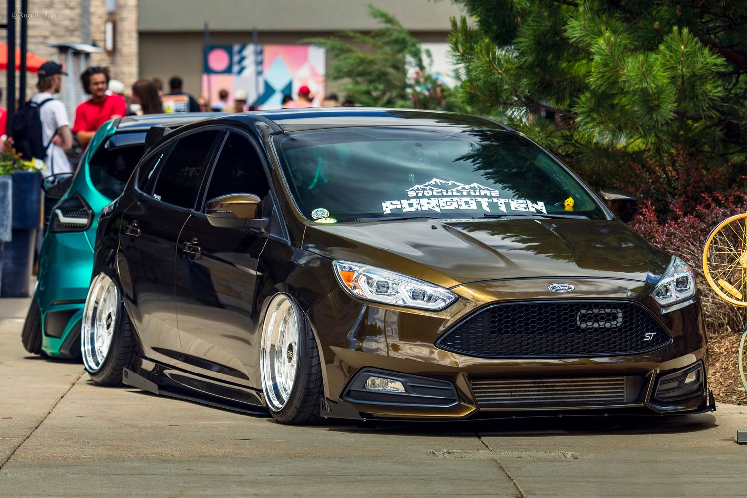 Lowered brown Ford Focus ST with custom stance and white windshield banner.