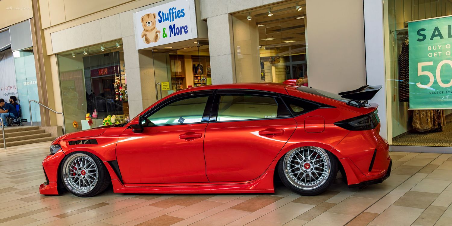 A widebody red Honda Civic Type R on large BBS wheels displayed inside a shopping mall.