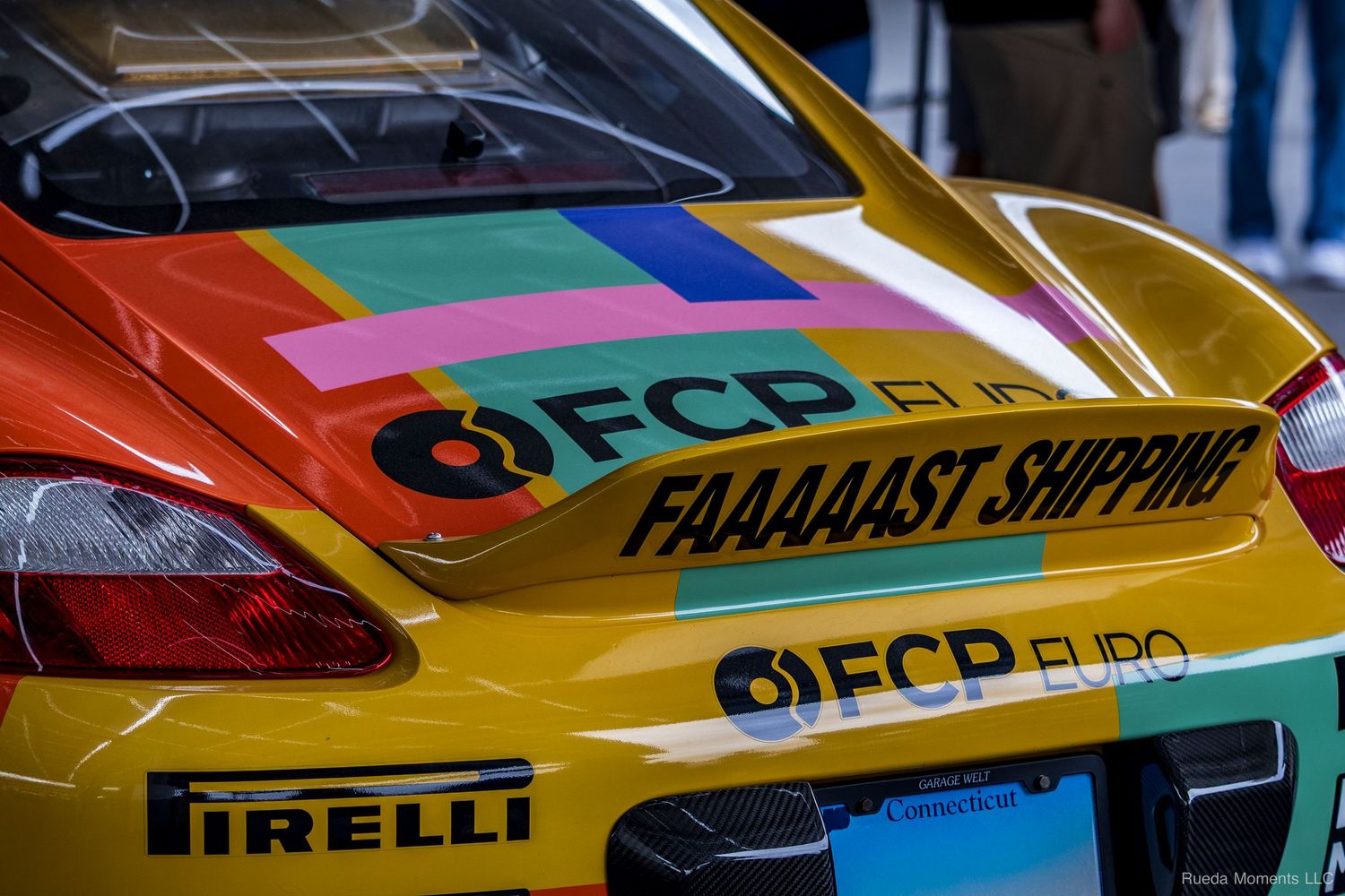 Yellow FCP Euro race car with colorful livery and FAAAAAST SHIPPING decal at a motorsport event.