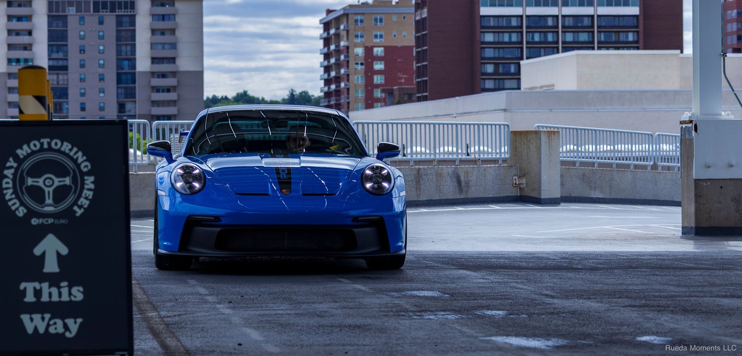 Blue Porsche 911 GT3 front view on a rooftop parking deck.