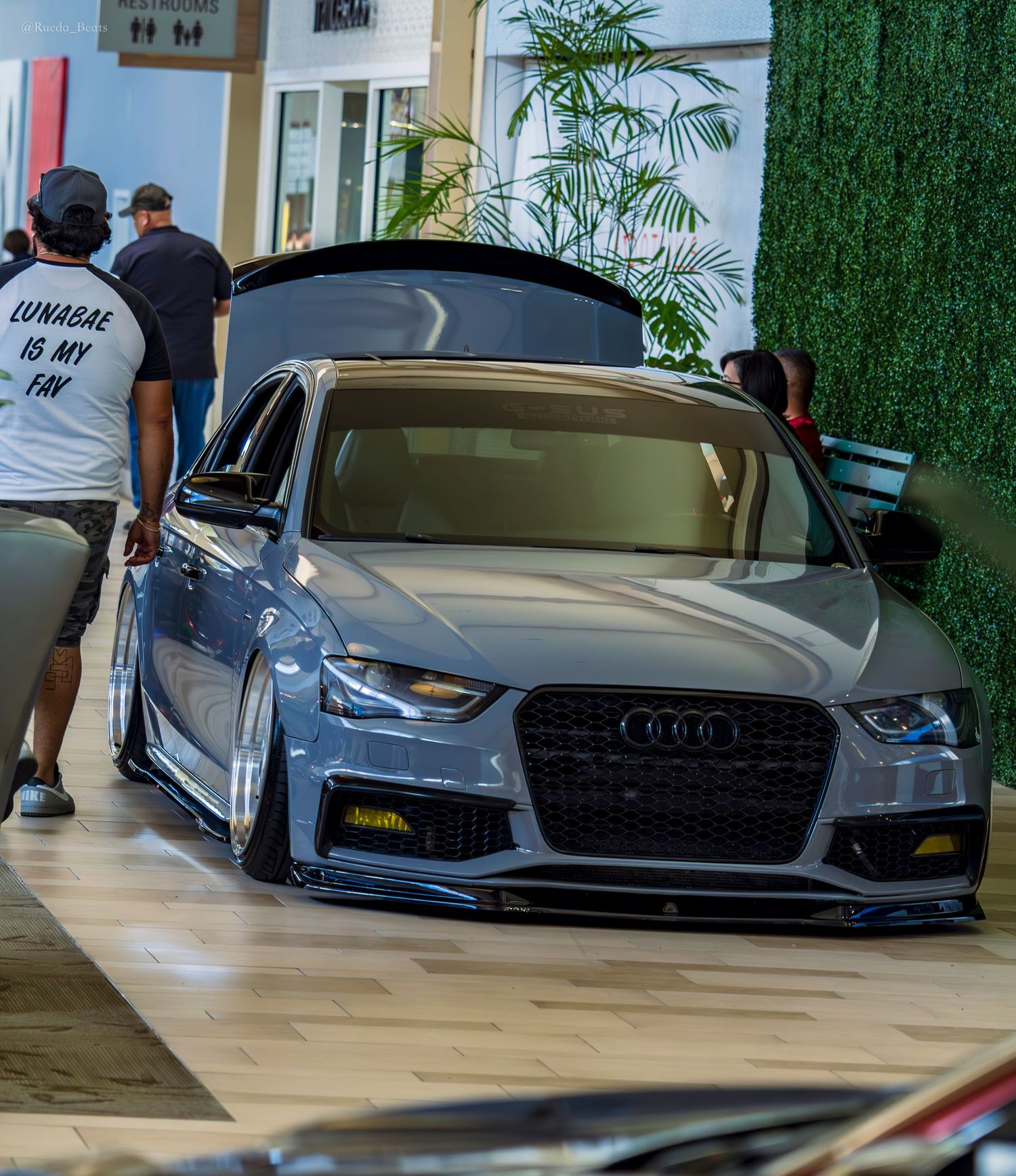 Silver bagged Audi A4 with aggressive stance and black grille on display at indoor car show.