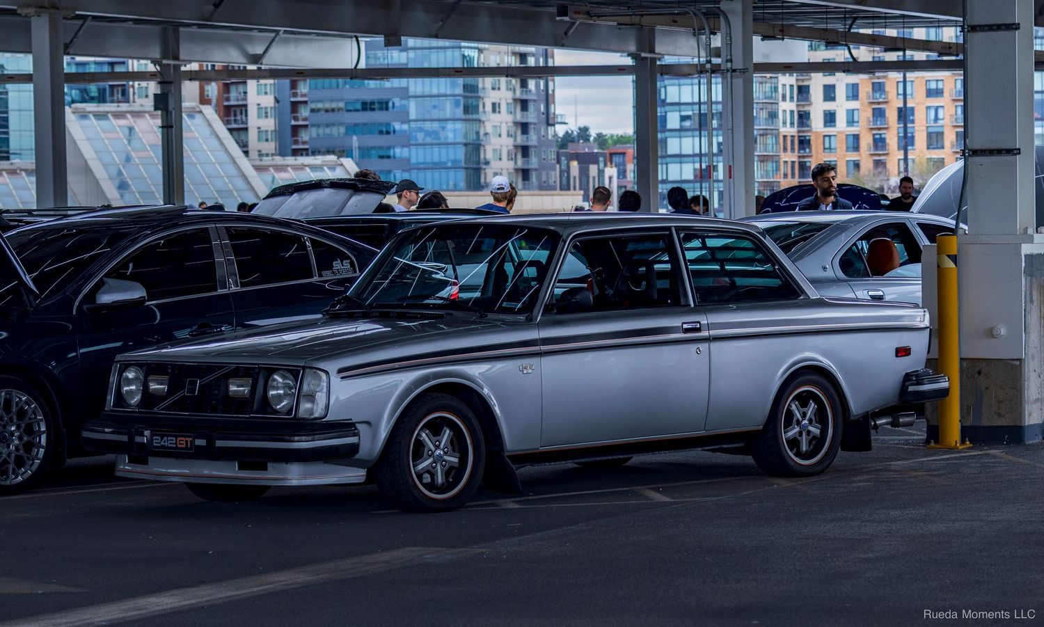 Classic silver and black Volvo 242 parked in a multi-level parking garage car meet.