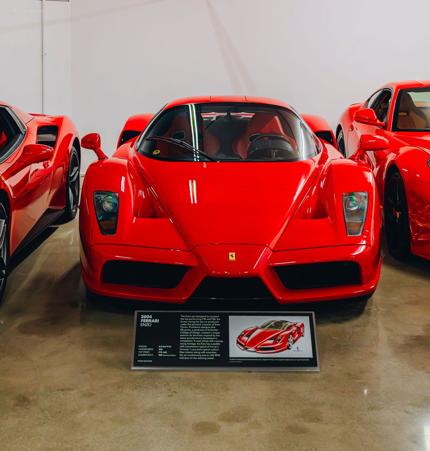 Red Ferrari Enzo supercar on display at a museum with informational placard in front.