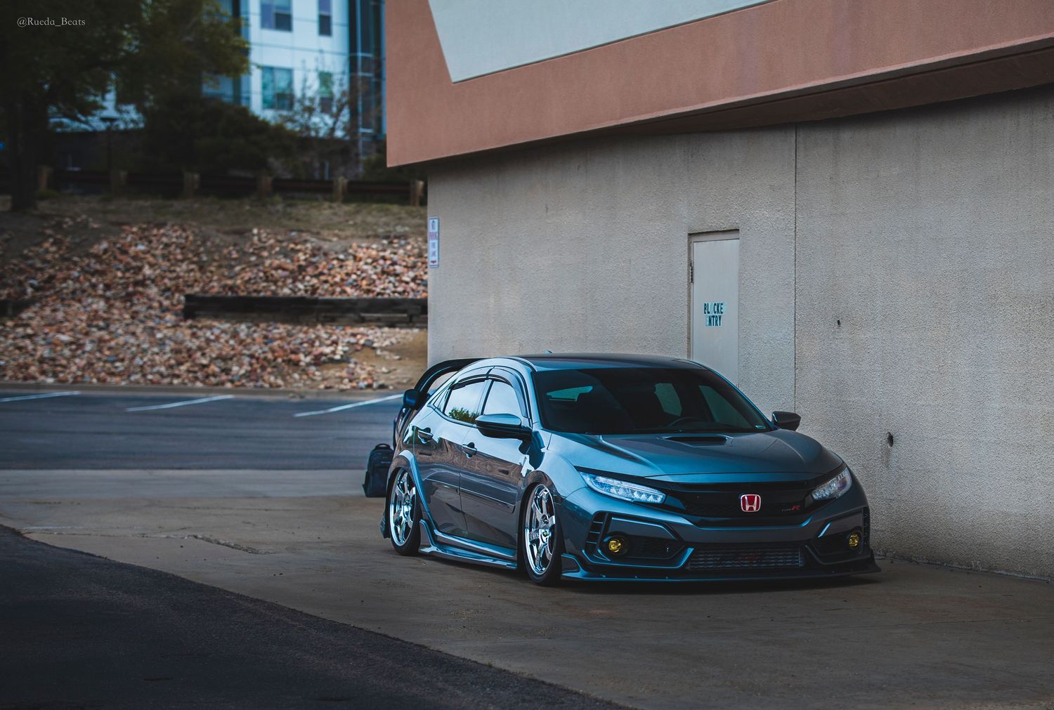 Bagged dark blue Honda Civic Type R parked beside a building.