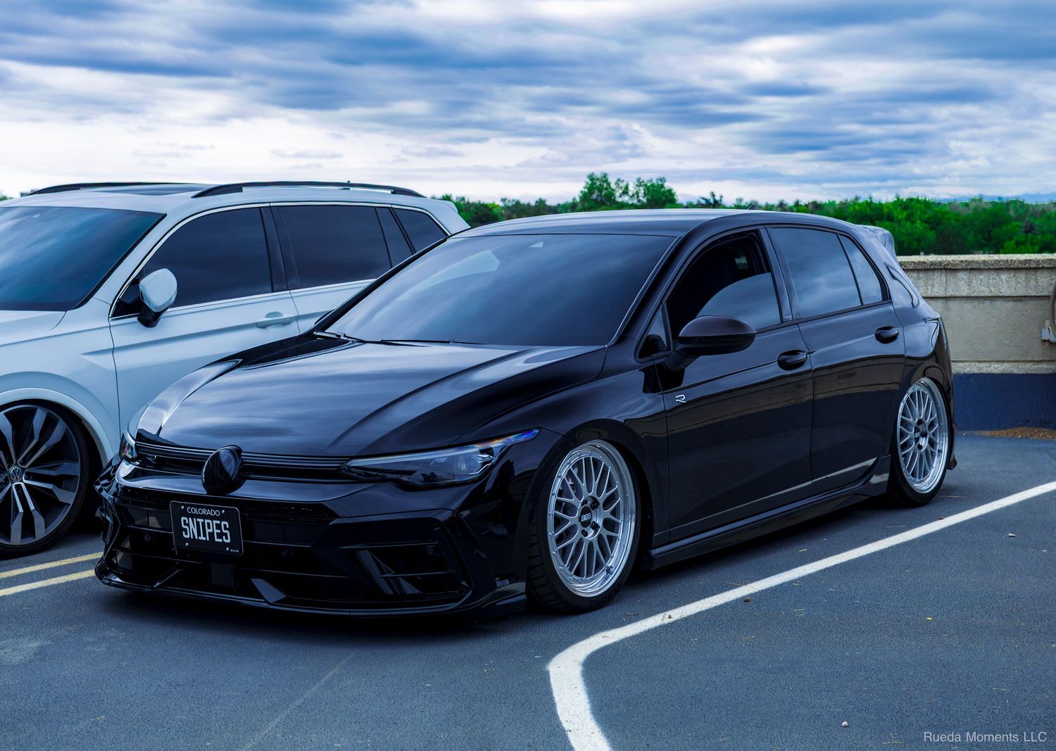 Slammed black Volkswagen Golf R with BBS wheels parked in a lot at a car meet.