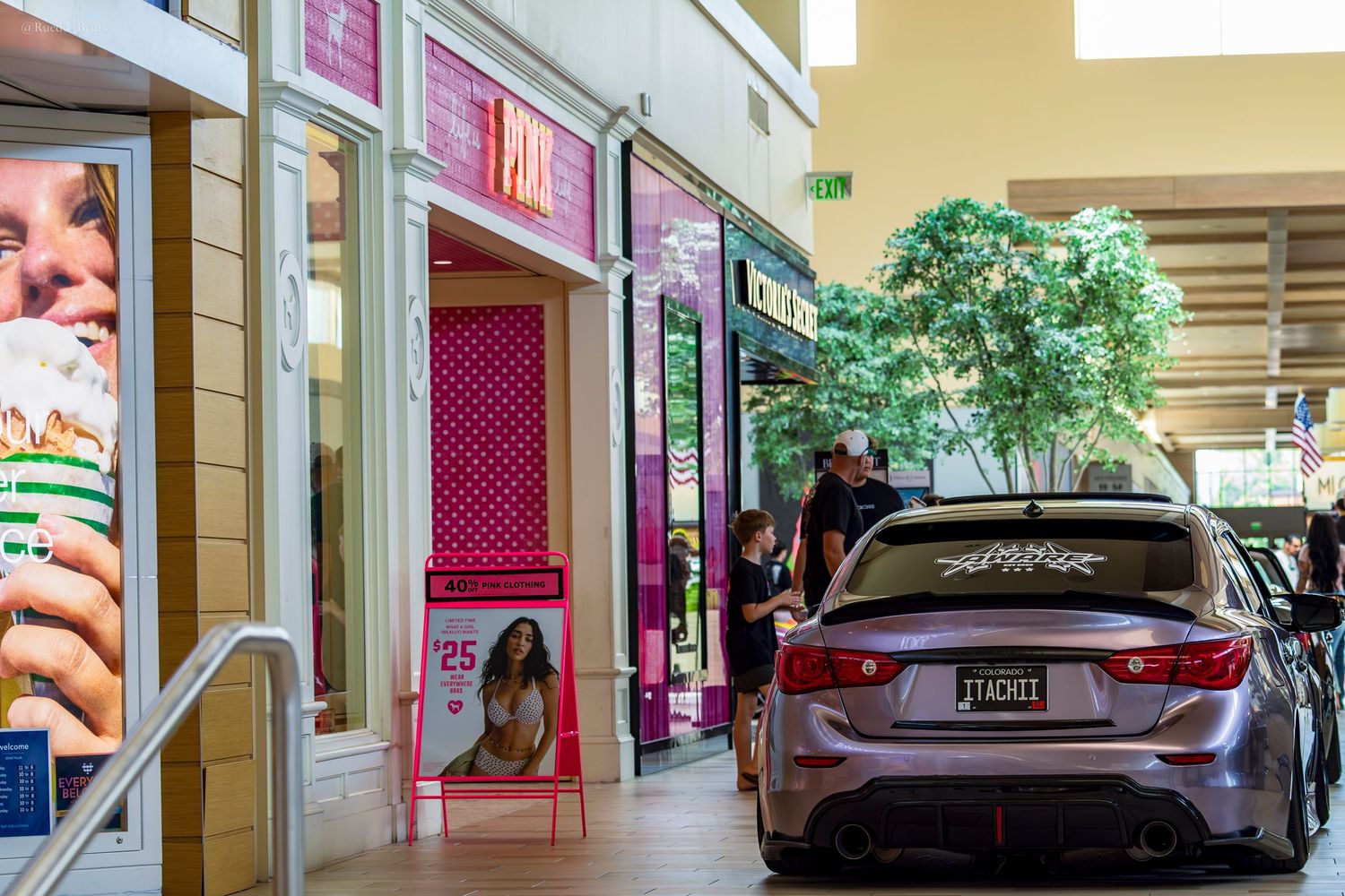 Silver Alfa Romeo Giulia with custom plate parked inside shopping mall near Victoria's Secret store.