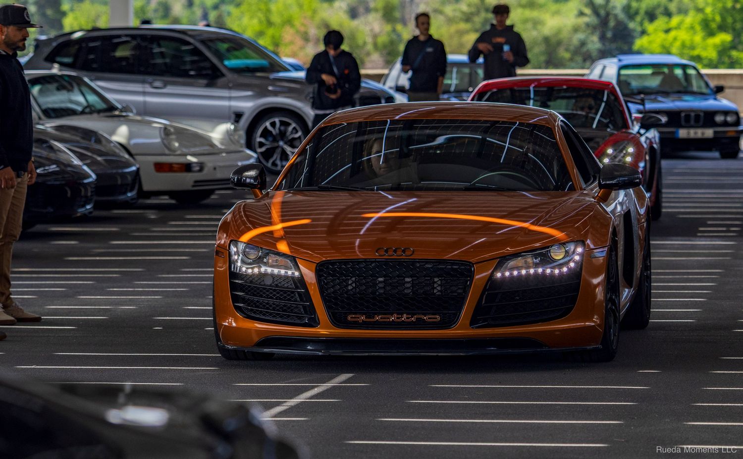 A stunning orange Audi R8 with custom lighting displayed at an outdoor automotive car meet.