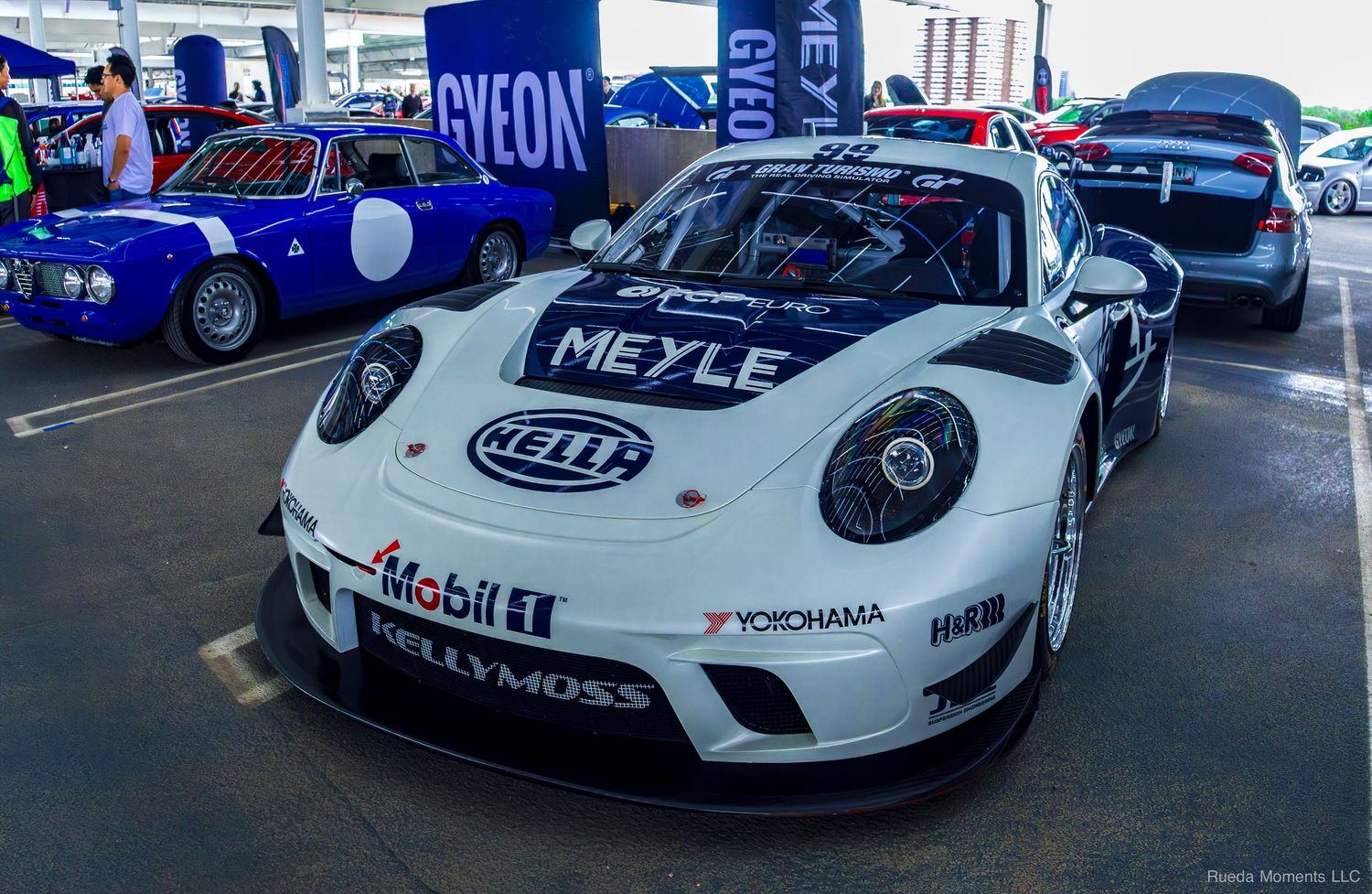 White Porsche race car with Meyle and Mobil 1 sponsorship decals on display at an automotive racing event.