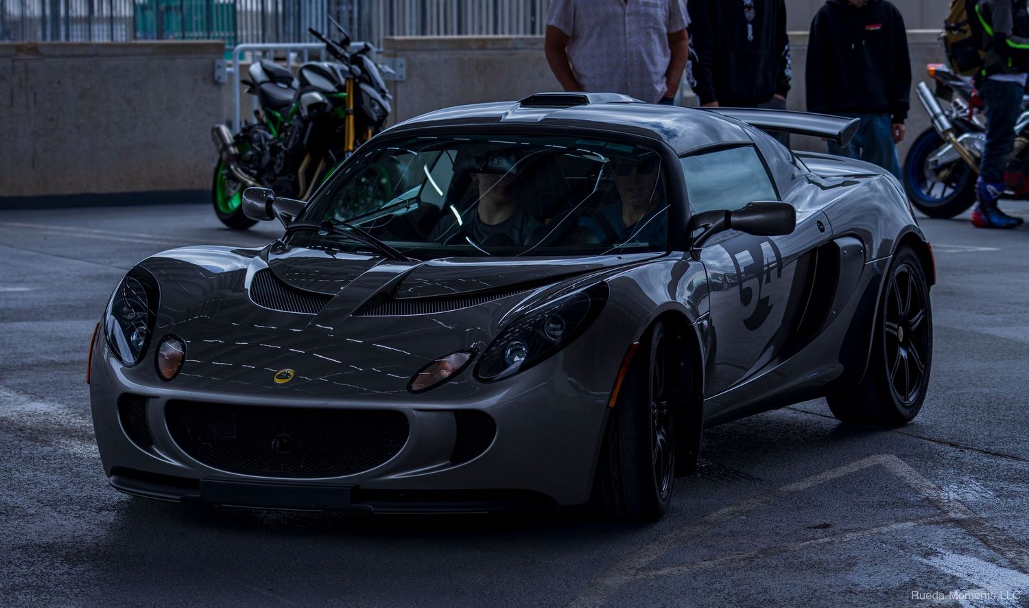 Dark gray Lotus Elise sports car parked at an outdoor car meet.