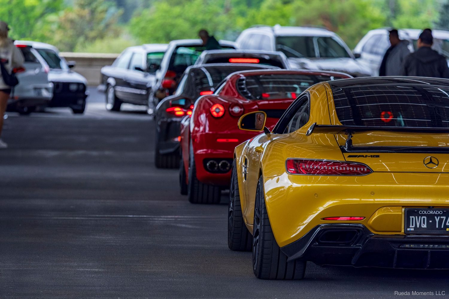 Yellow Mercedes-AMG GT and red Ferrari lined up at an outdoor exotic car meet event.