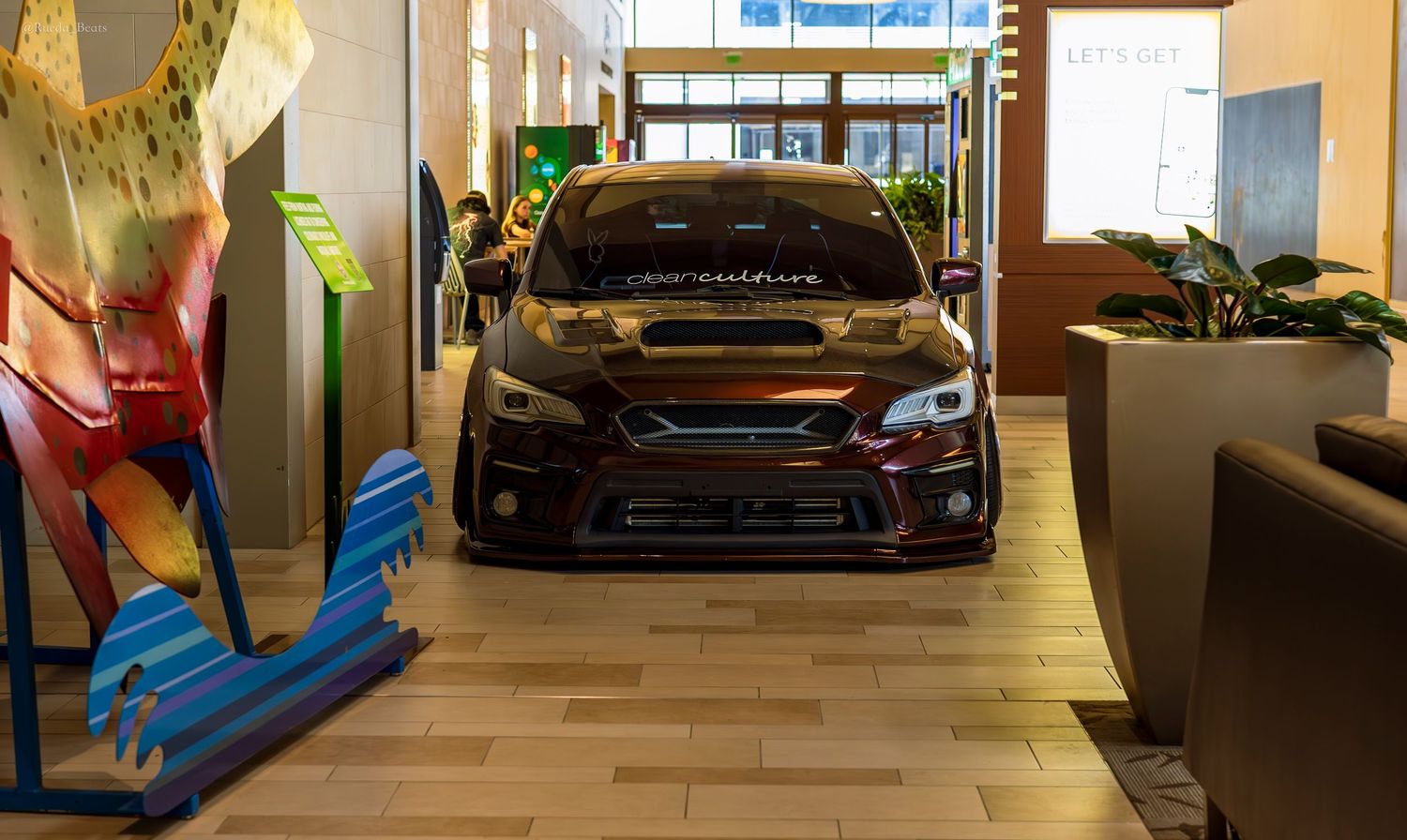 Dark Ford Focus RS with racing livery on display at an indoor mall car show.