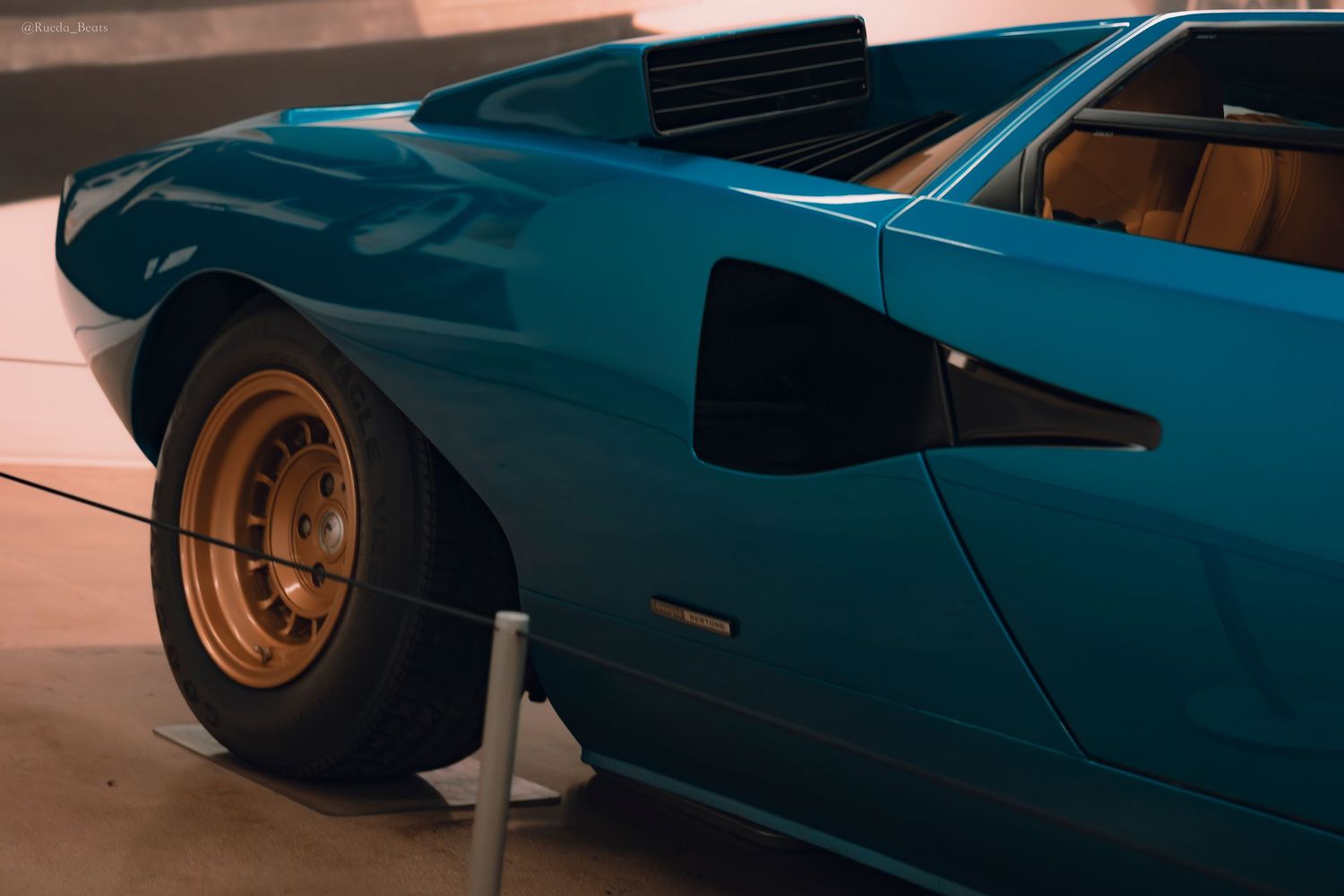 Close-up of blue Lamborghini Countach rear quarter panel showing gold wheel and air intake vent.