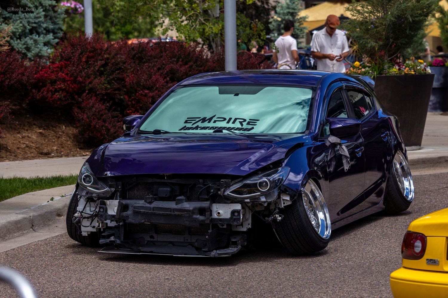 Slammed dark blue hatchback with Empire windshield banner at outdoor car meet.