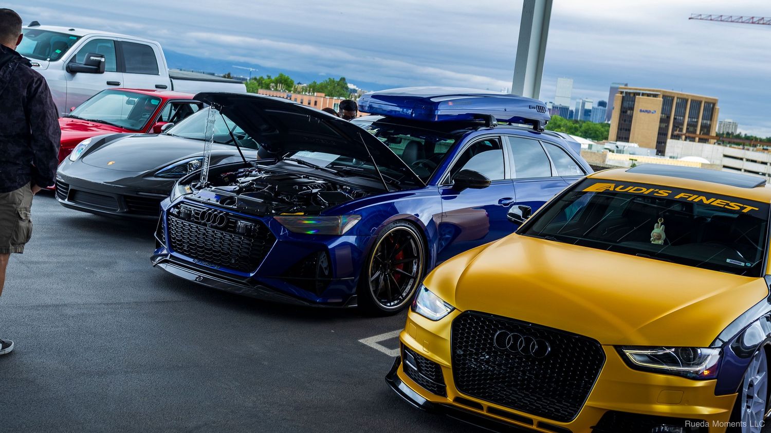Blue and gold modified Audi vehicles with open hoods on display at an outdoor car show.