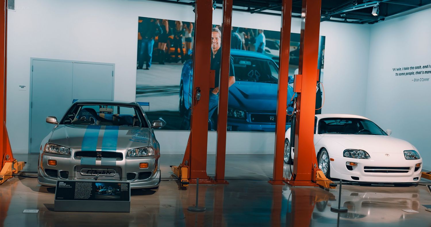 Nissan Skyline GT-R and white Toyota Supra on display at Fast and Furious movie car museum.