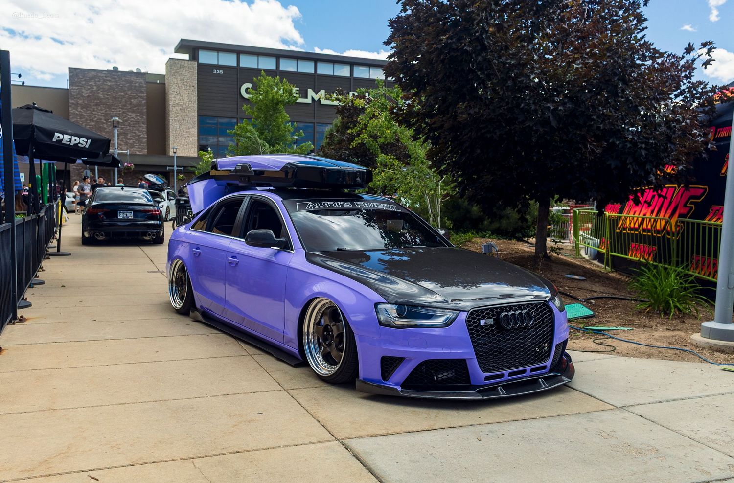 Purple widebody bagged Audi RS4 with carbon hood and roof box at a car meet.