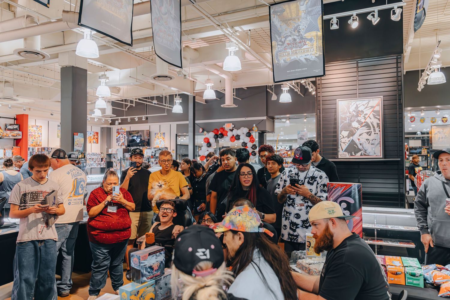 Large crowd of trading card collectors browsing and shopping inside a brightly lit retail store.