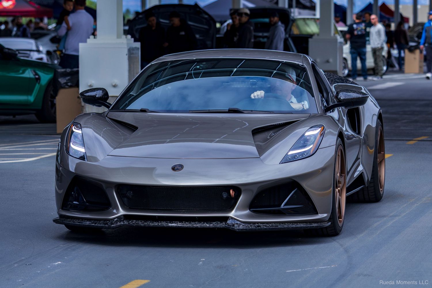 A matte gray Lotus Emira sports car on display at an automotive enthusiast car show.