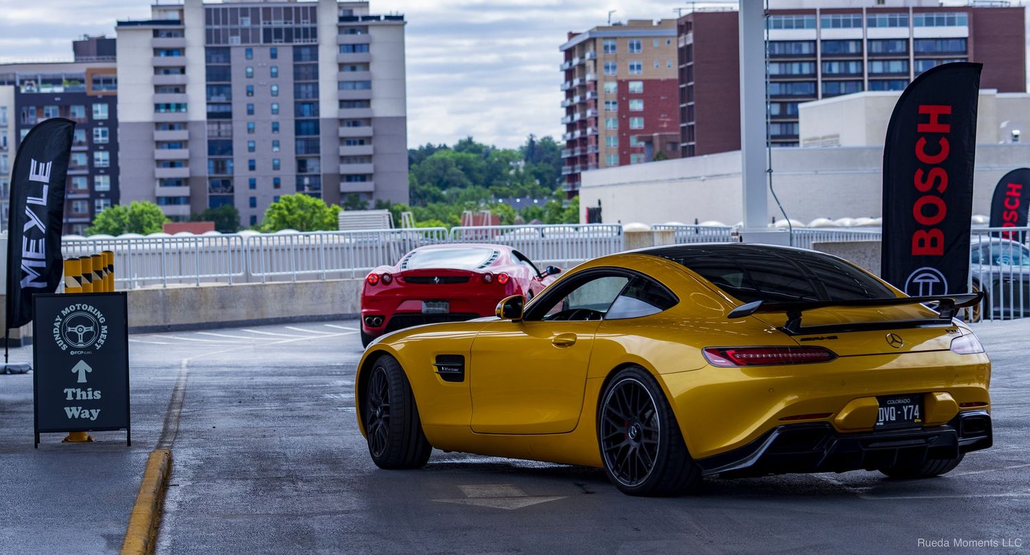 Yellow Mercedes-AMG GT and red Ferrari parked at a Bosch-sponsored car show.