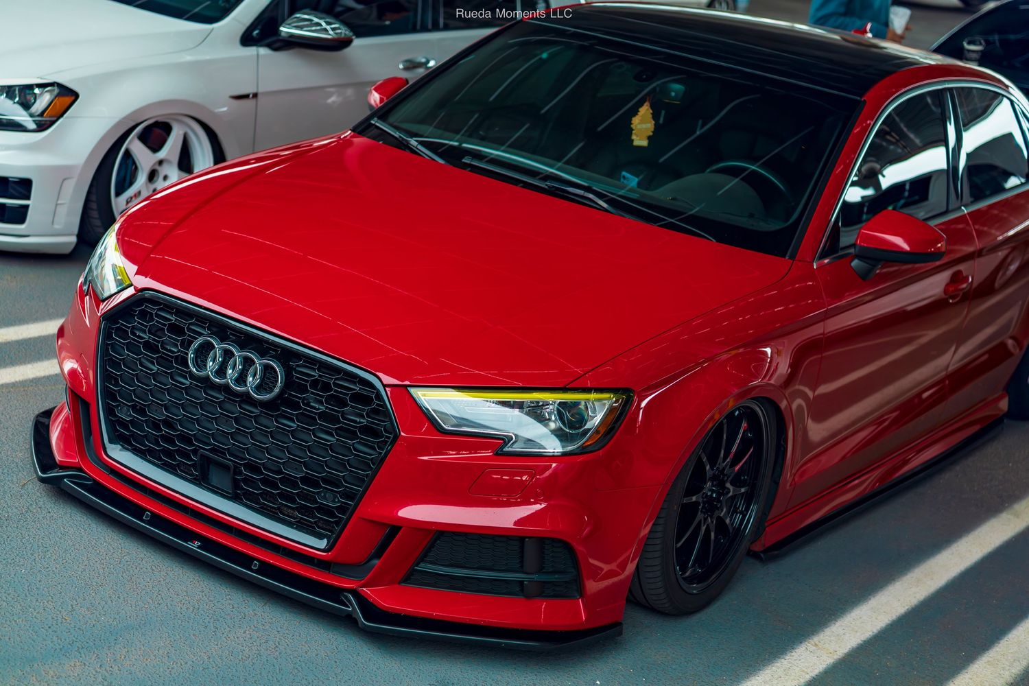 Close-up of a slammed red Audi S3 with RS3 front bumper conversion and carbon lip spoiler.