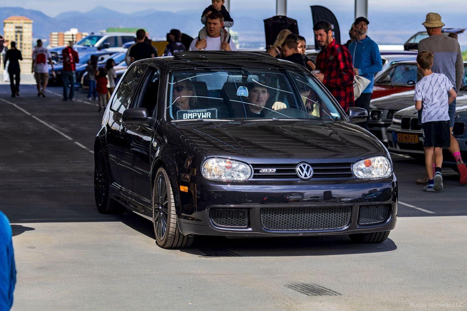 Black Volkswagen Golf MK4 with aftermarket wheels parked at an outdoor automotive enthusiast event.