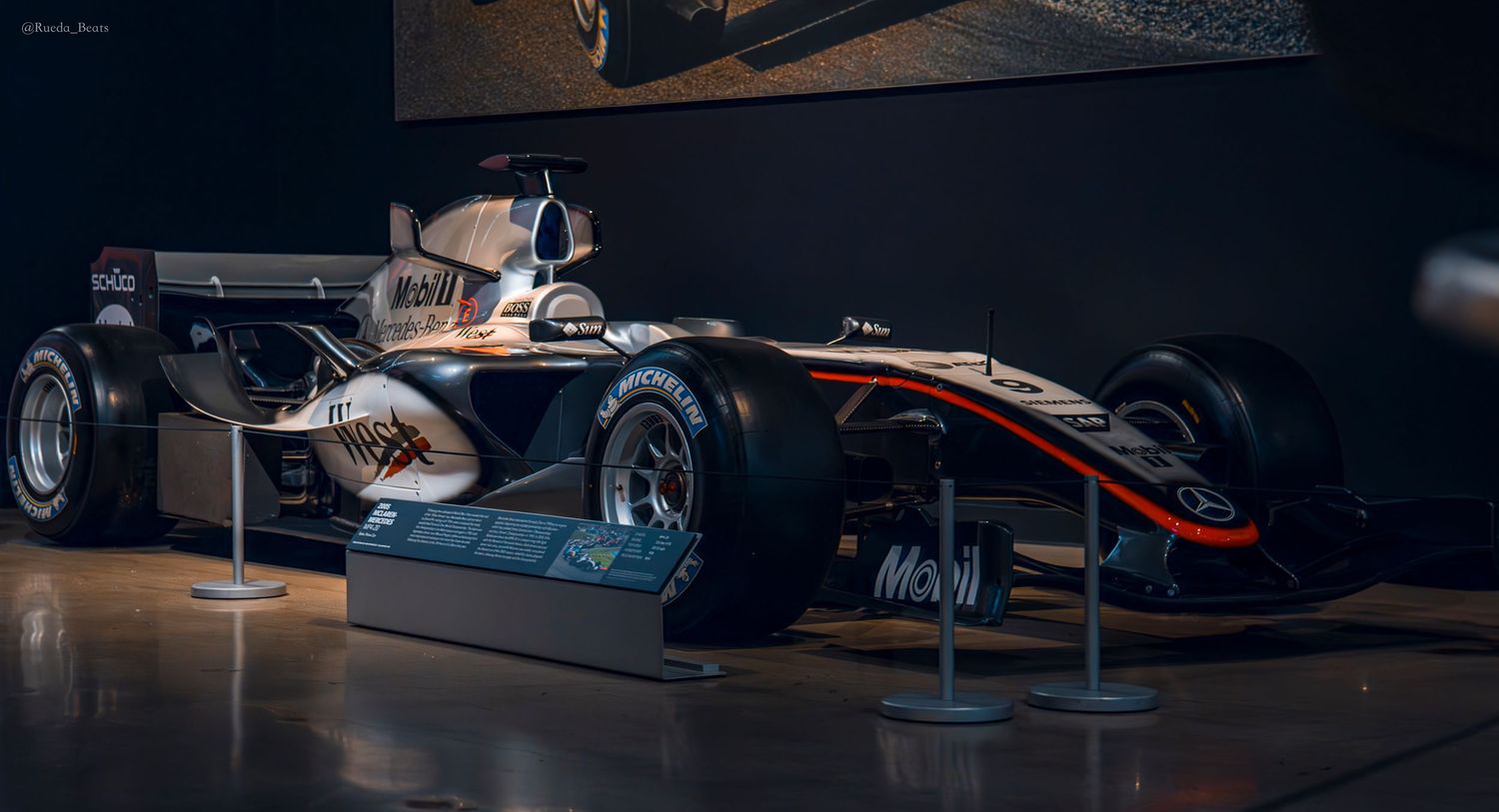 Silver McLaren Formula 1 race car with Mobil 1 sponsorship displayed in a museum.
