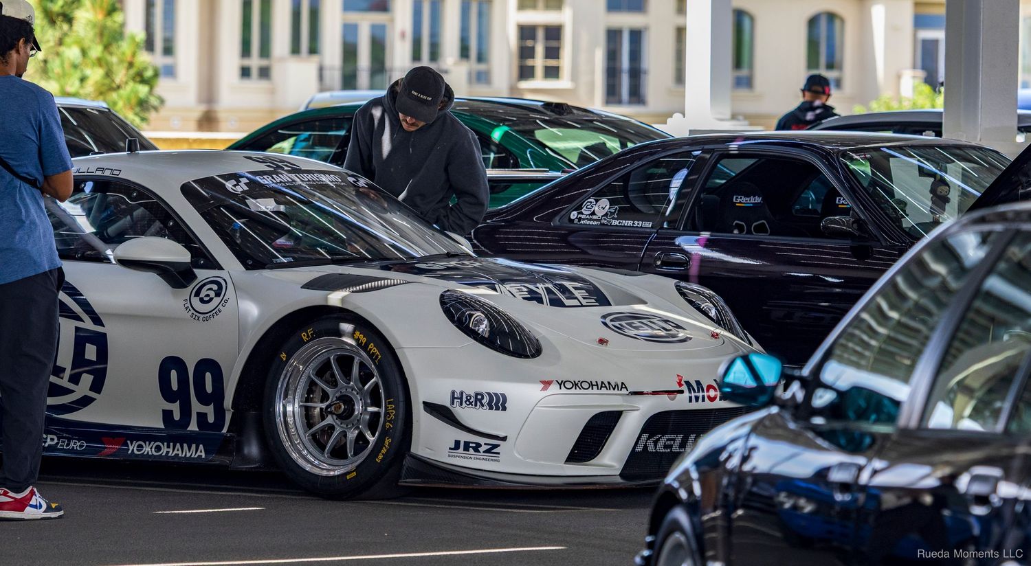 White Porsche GT3 race car number 99 with racing livery displayed at an outdoor automotive event.