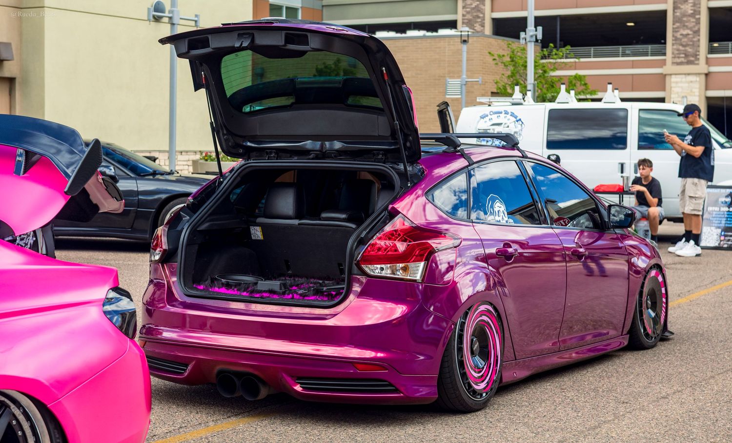 Purple lowered Ford Focus ST hatchback with open trunk at an outdoor car show.