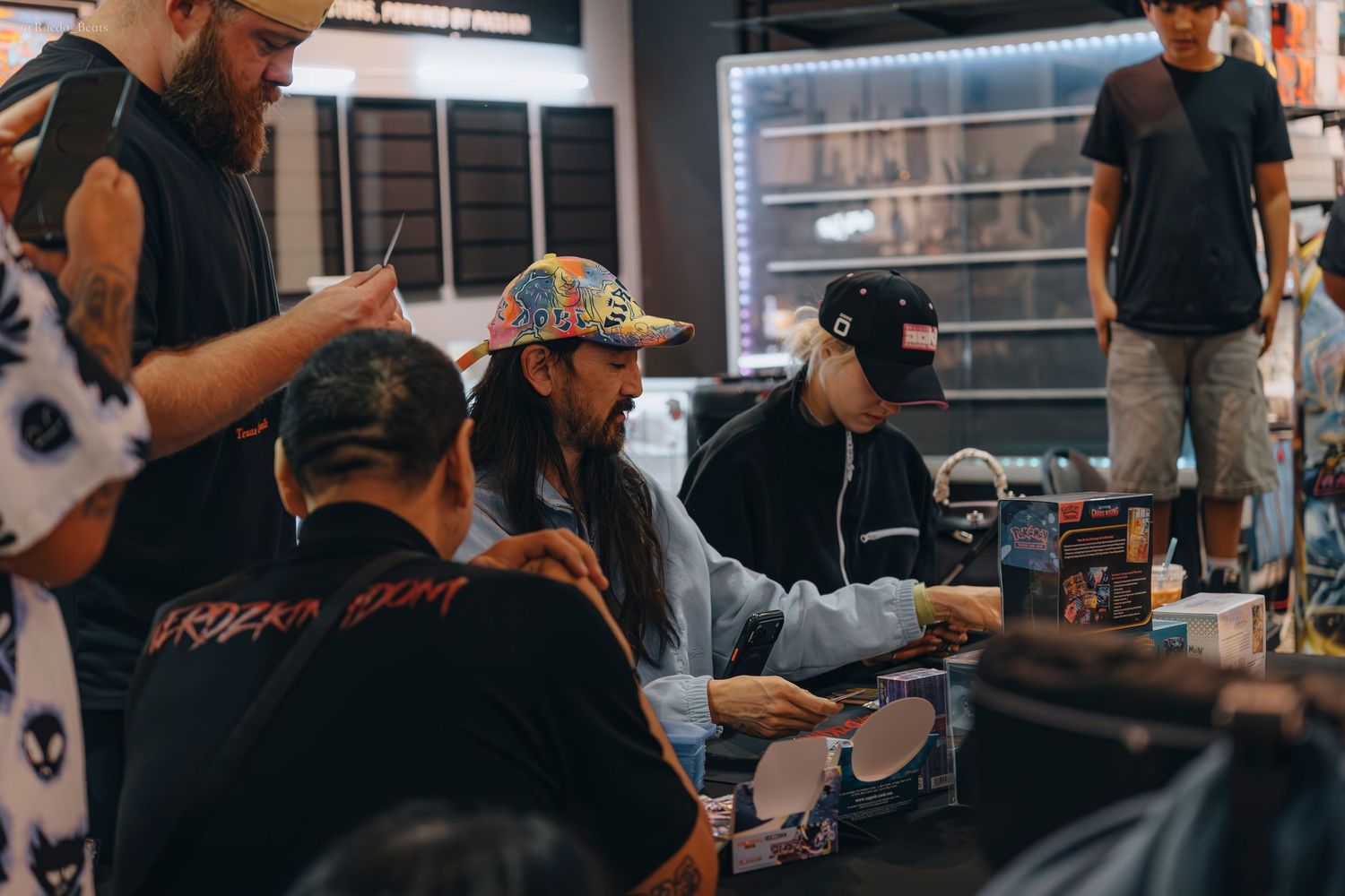People gathered around a retail counter examining trading cards at a busy collector shop event.