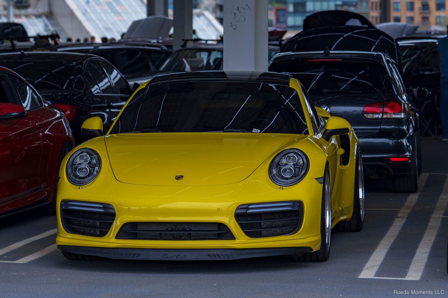 Bright yellow Porsche 911 Turbo S parked at an indoor automotive car show event.