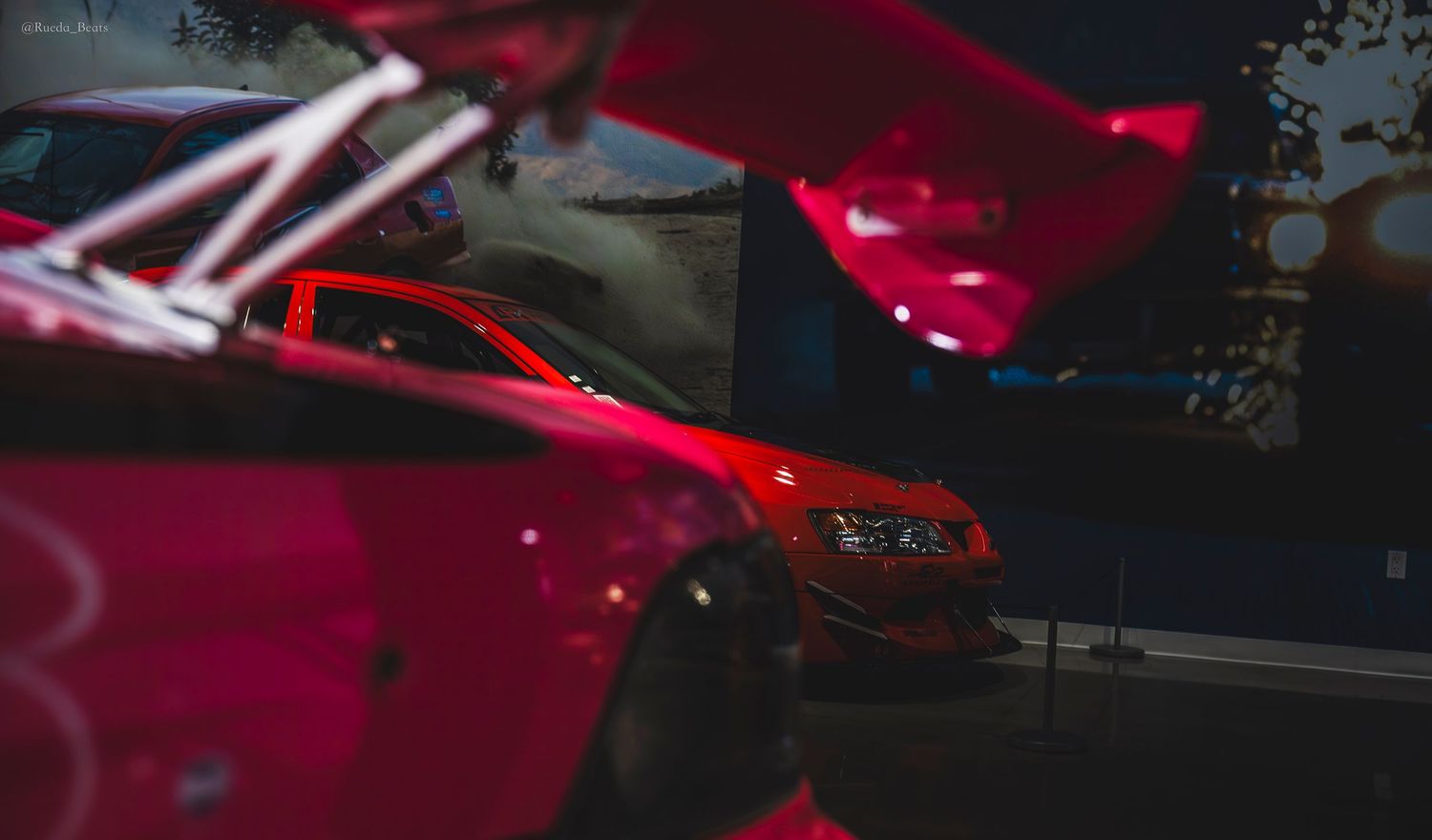 Red sports car with dramatic lighting on display at Fast and Furious movie car exhibition.