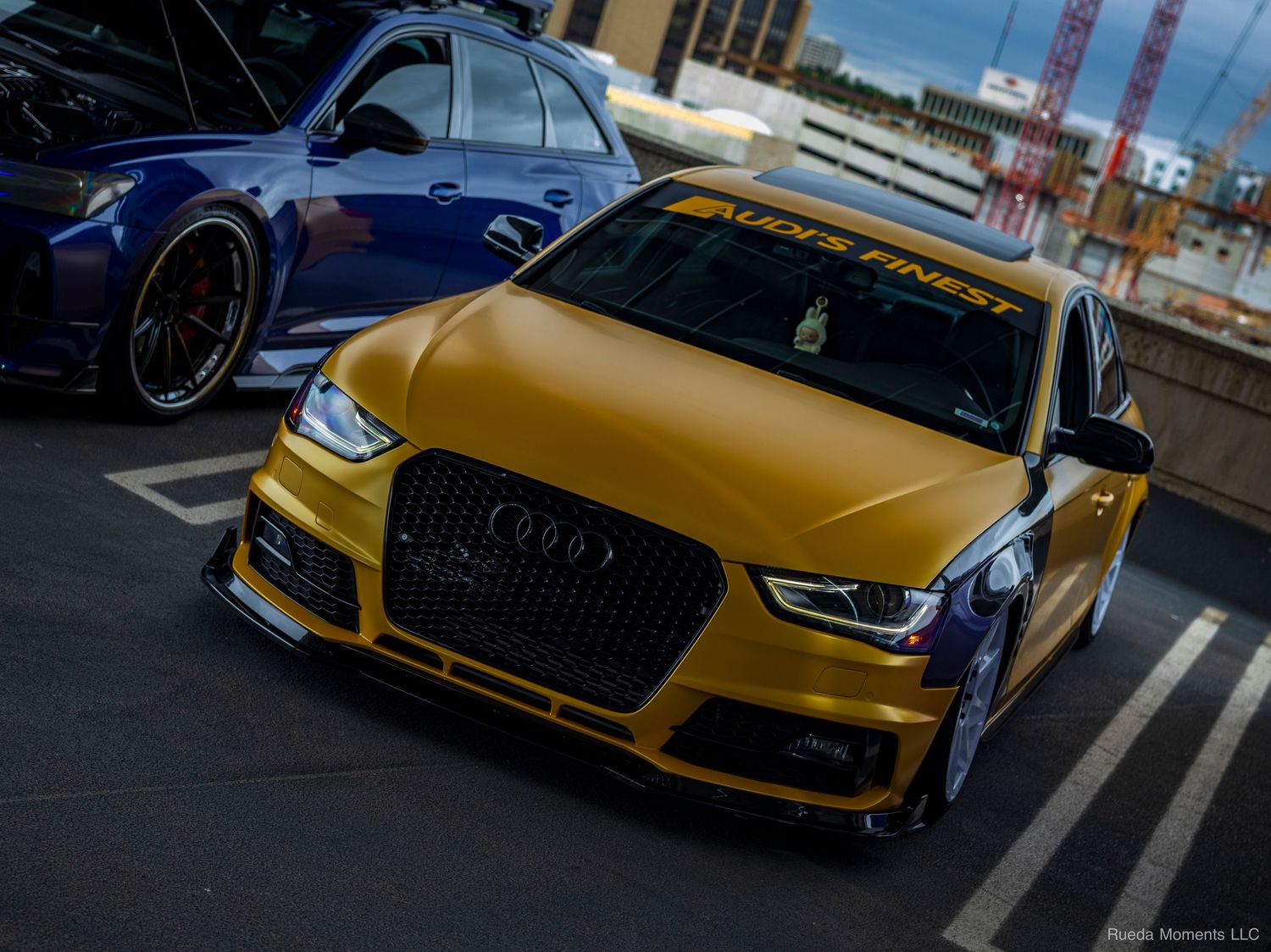 Modified gold Audi A4 with wide body kit and Audis Finest banner at a car meet.