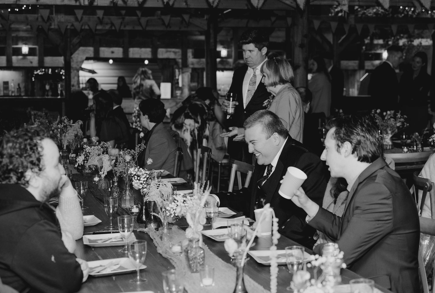 Black and white photo of elegantly dressed guests dining at a decorated banquet table.