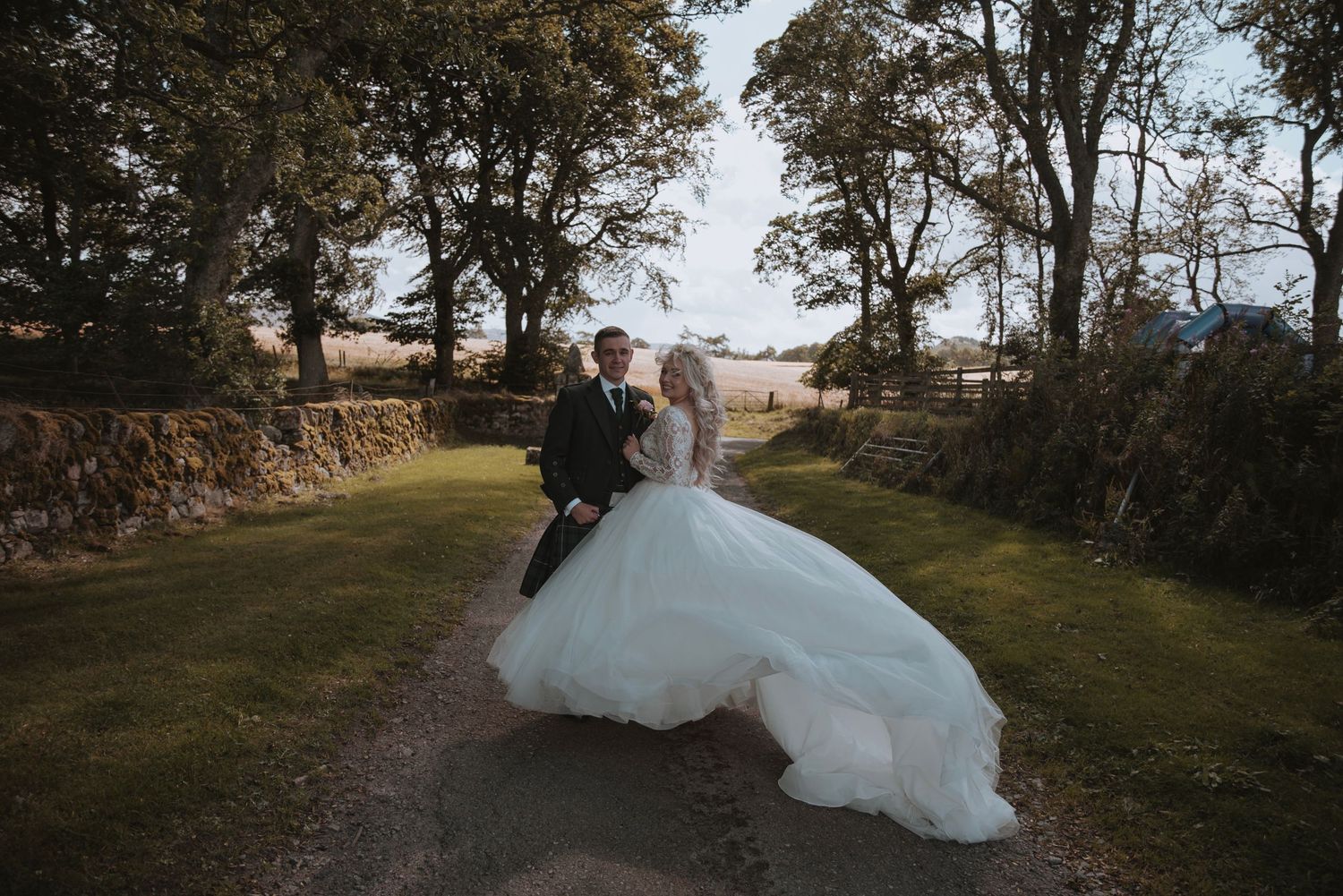 Bride and groom walking together on a garden path with flowing wedding dress.