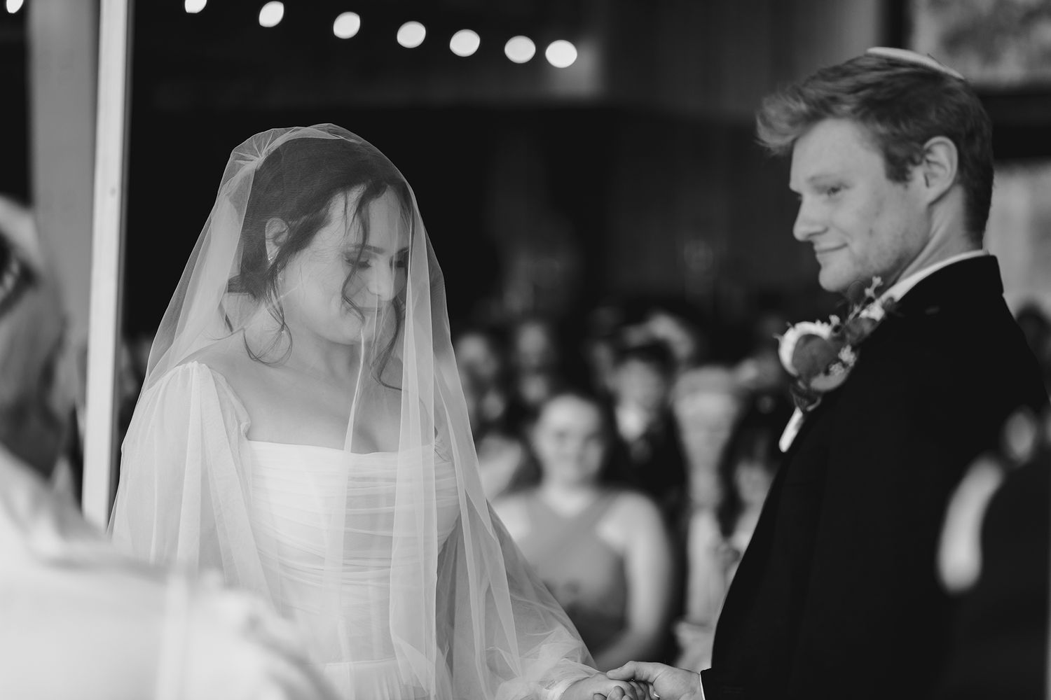 Black and white photo of bride and groom exchanging vows at wedding ceremony altar.