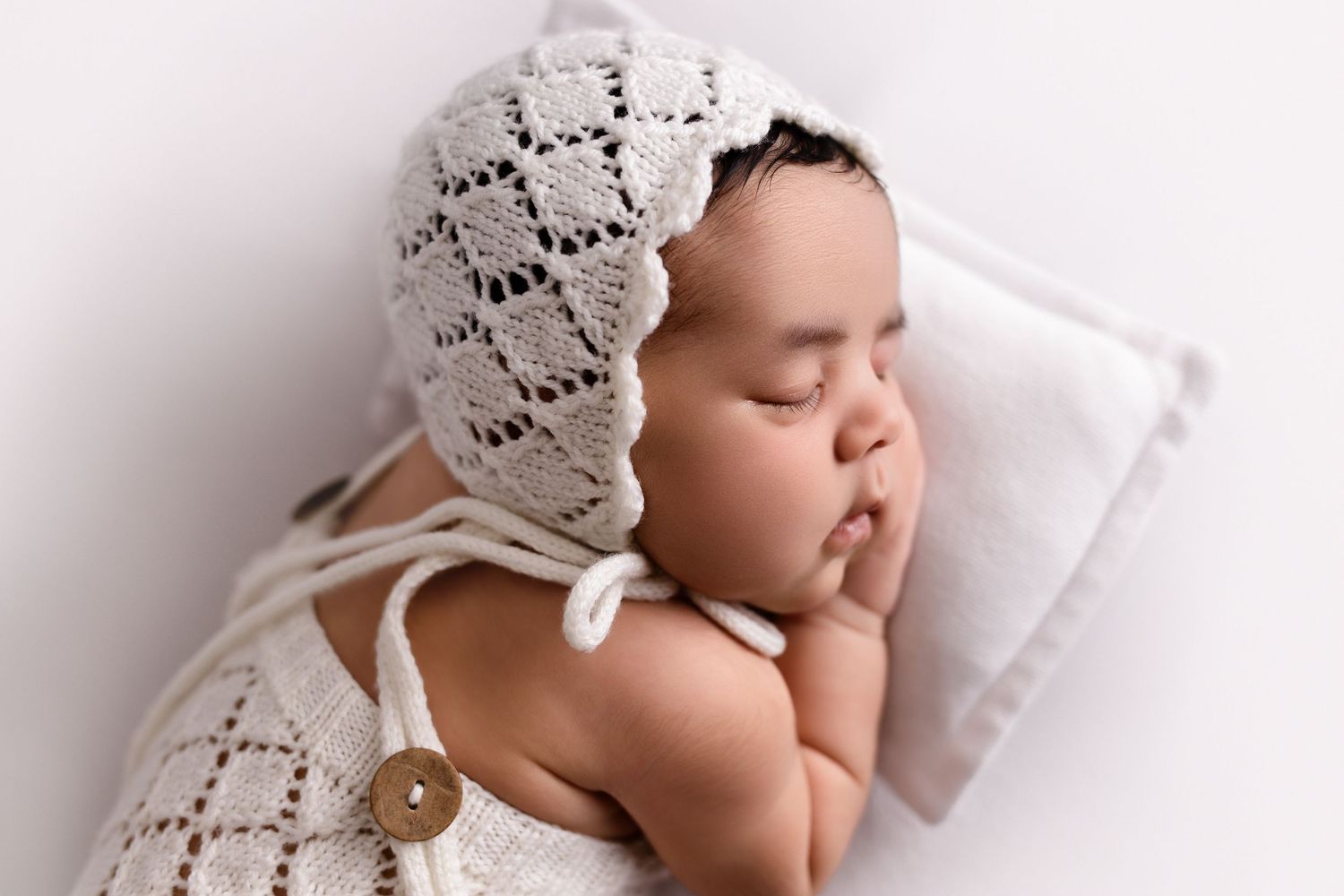 Closeup profile of newborn girl snuggled up on a tiny pillow during newborn photo session with Mikelle Allaire at The Essence Photography.
