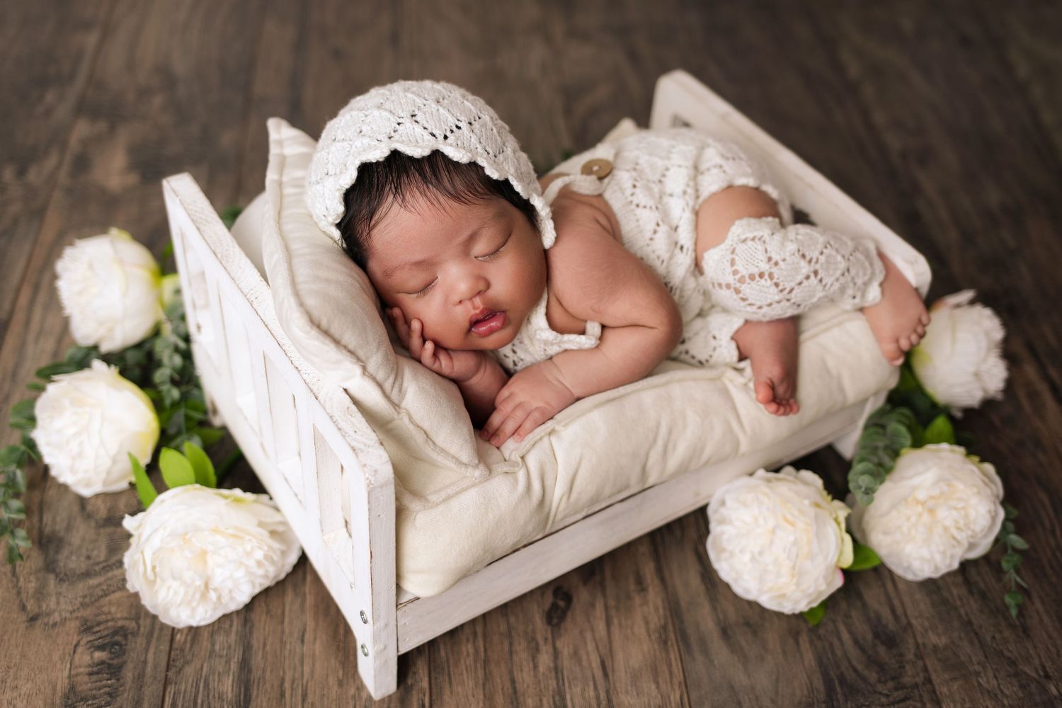 Adorable newborn baby, snuggled up on a tiny bed during a luxury photo session at The Essence Photography by Mikelle.