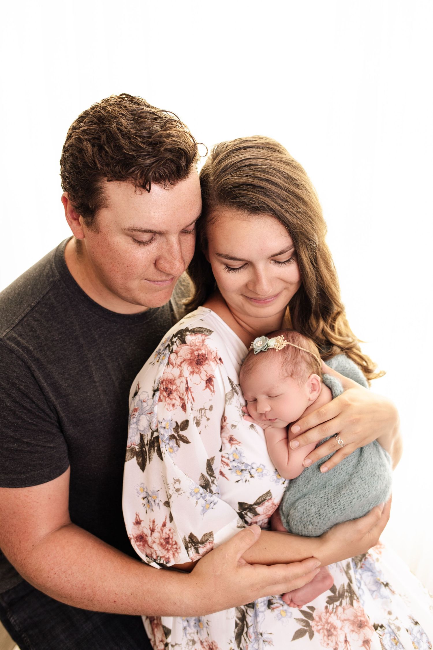 Parents looking down lovingly while holding their newborn baby girl during a family newborn photography session in the East Kootenays.
