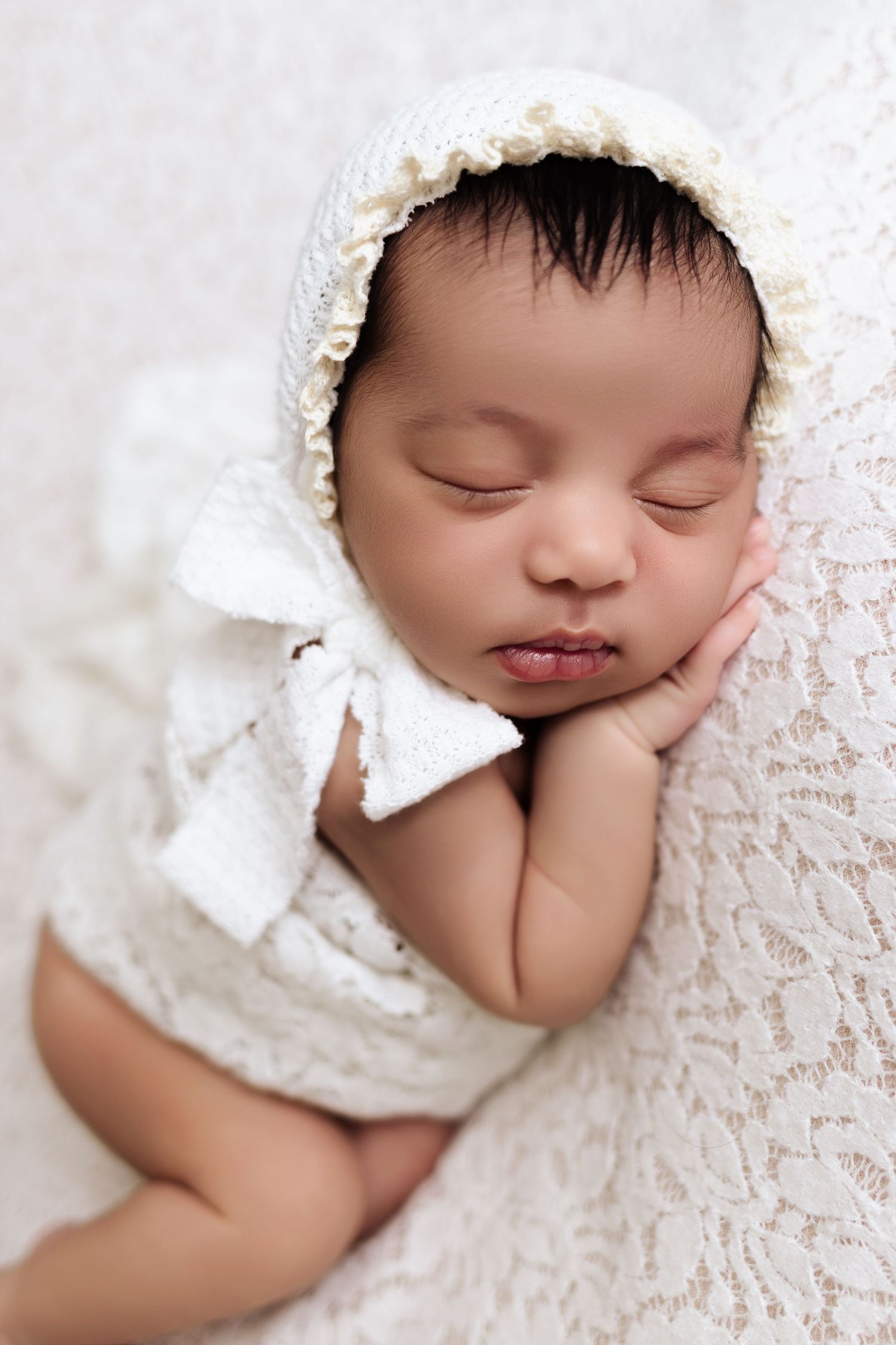 Beautiful baby girl posed naturally with bonnet tied with bow by Columbia Valley's newborn photographer, Mikelle Allaire