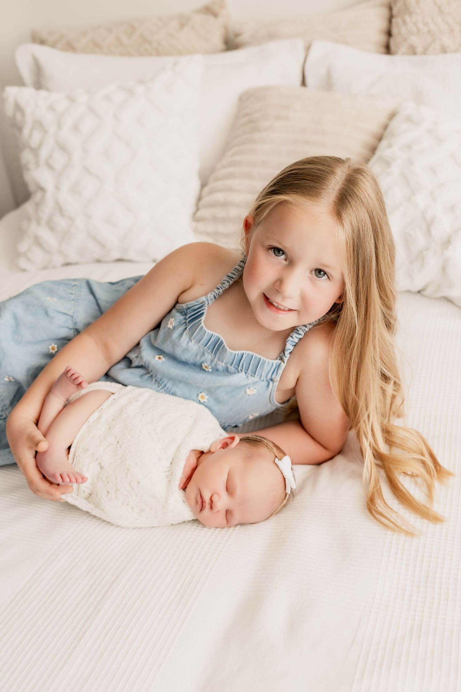 A big sister lays beside her newborn baby sister during a newborn and family photo session by Invermere photographer, Mikelle Allaire.