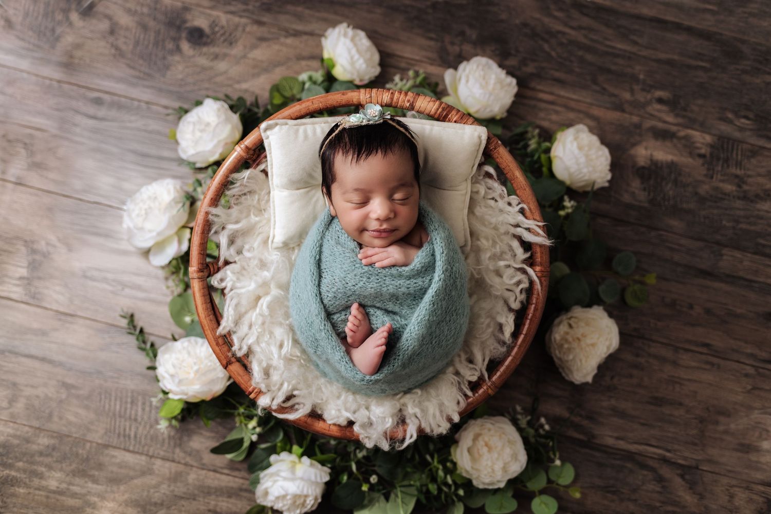 Newborn swaddled in soft blue blanket with feet peeking out on bamboo prop during photo session by Mikelle Allaire, The Essence Photography.