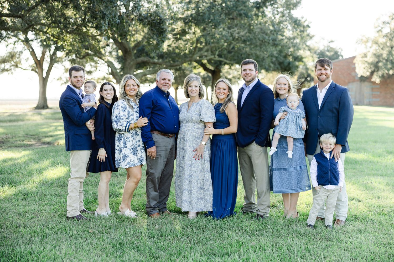 Extended family of ten posing together on green lawn for portrait photo.