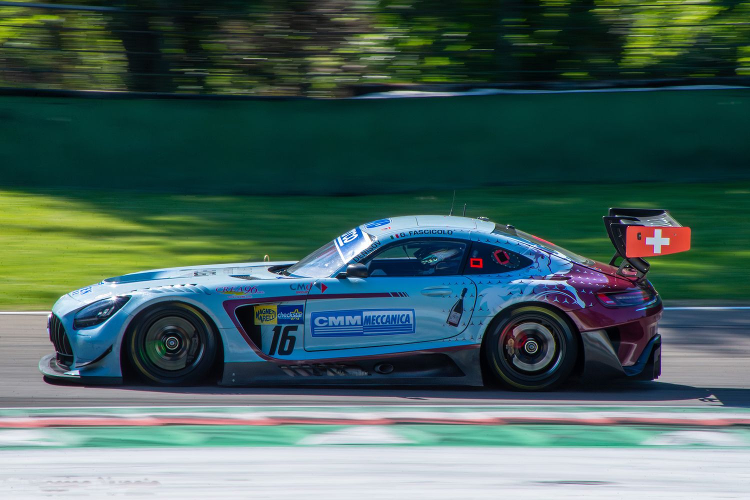 Blue and maroon Mercedes-AMG GT3 race car in a sharp panning shot at Imola circuit.