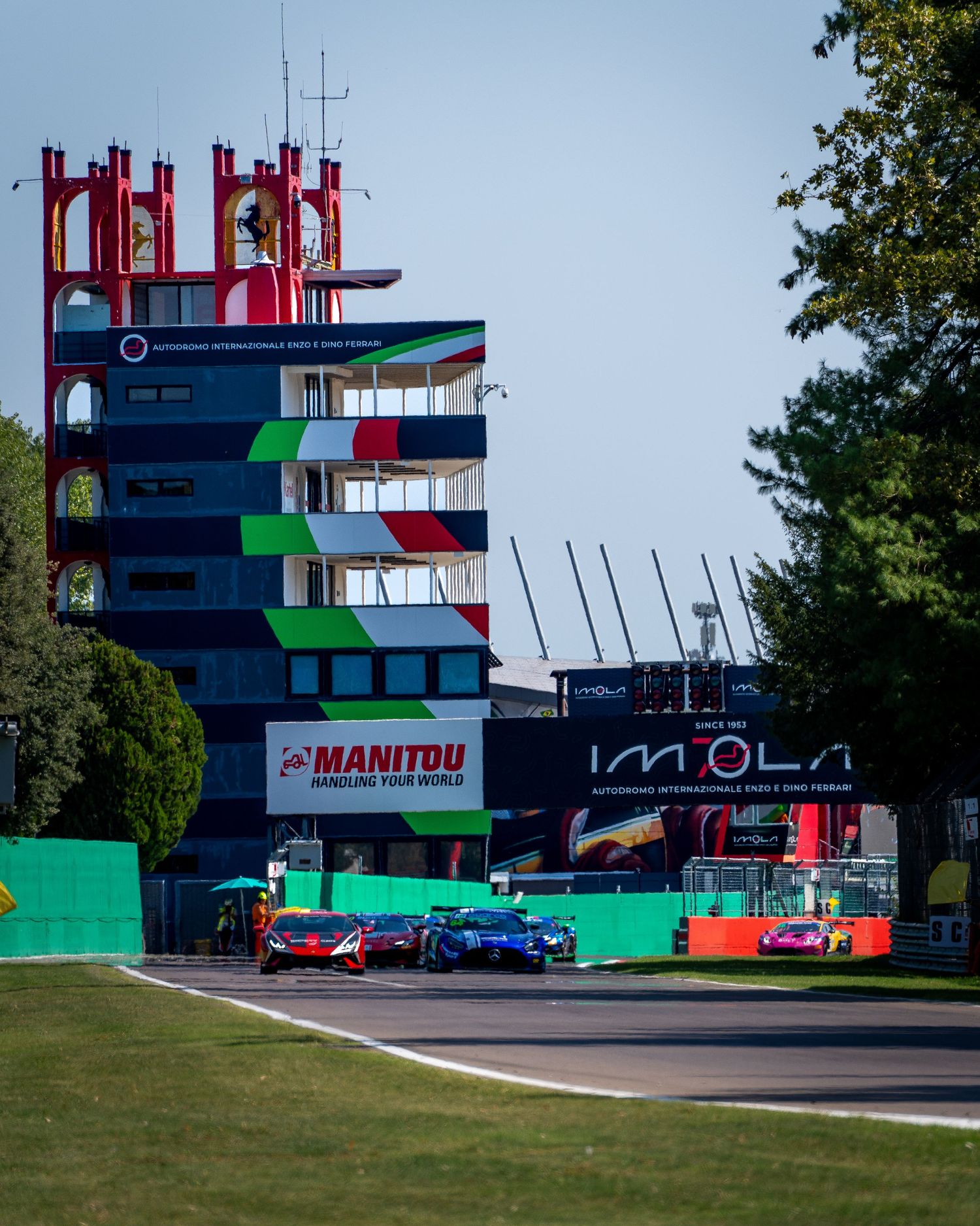 GT cars race past the iconic Imola pit tower and circuit buildings.