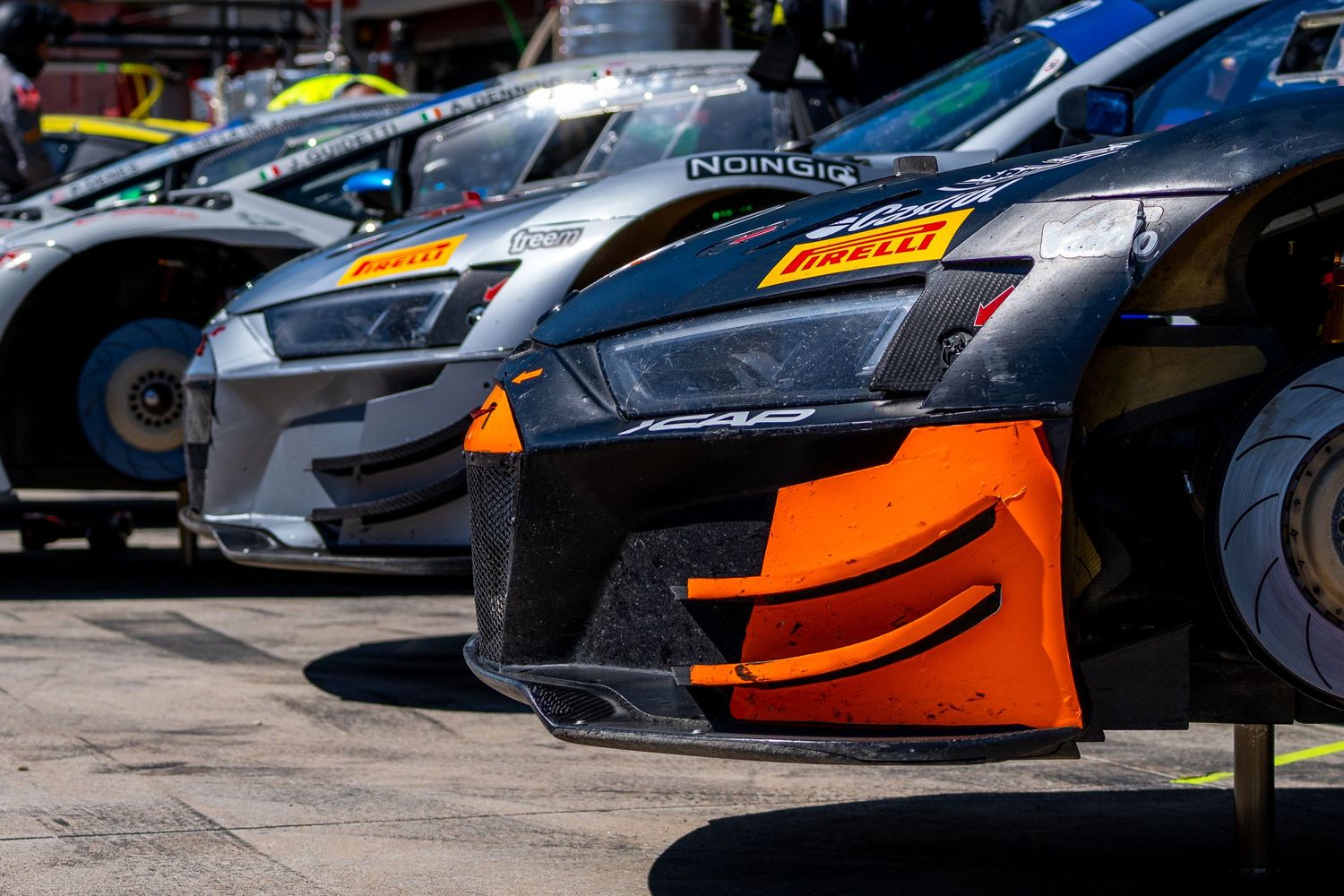 Close-up detail of Audi GT3 race cars in the pit lane showing their front splitter and aerodynamic bodywork.